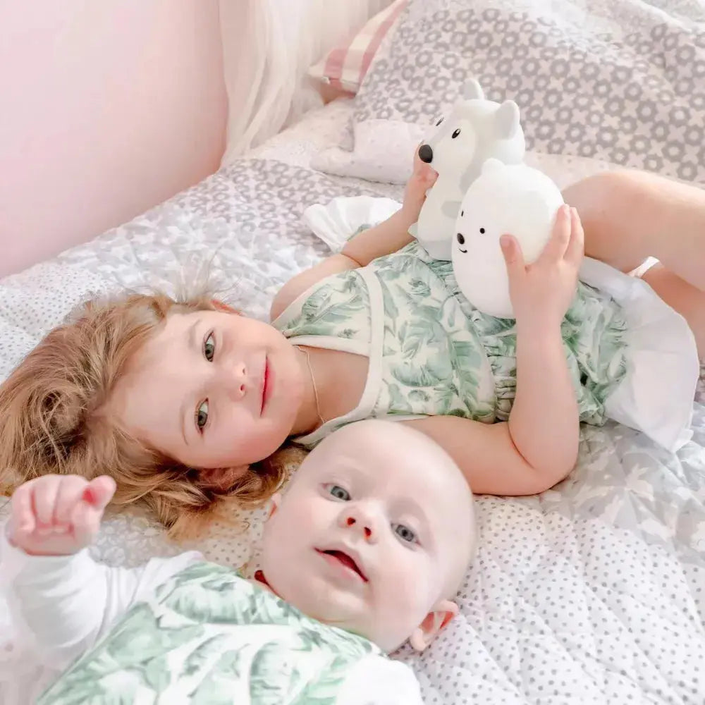 two children playing with their night lights in bed