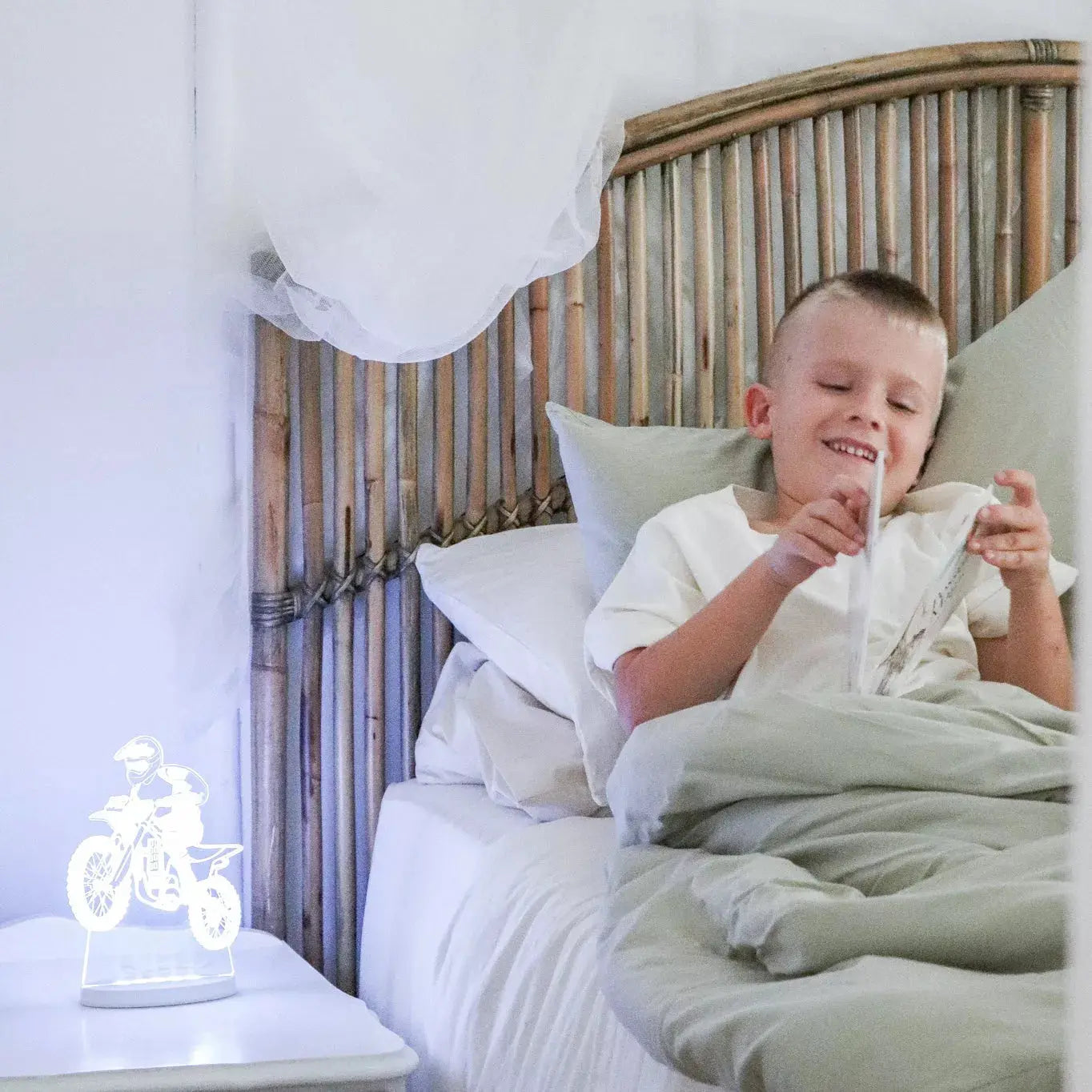 boy in bed, reading a story by his night light